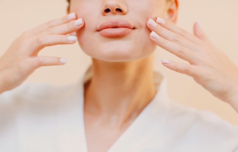 Mulher fazendo Yoga Facial, com mãos no rosto.